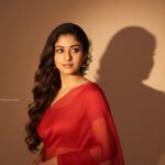 Convert, 4k HD realistic, A stunning portrait of a young Indian woman with long, dark, wavy hair cascading over her shoulders. She is wearing a translucent, elegant red saree draped over one shoulder, revealing a fitted blouse underneath. White flowers are tucked behind her right ear. She is looking slightly to her right, with a soft, serene expression. I want same face as I uploaded no alternation 100 percent
The background is a plain, warm-toned wall, illuminated by a warm light source from the right, creating a distinct, soft-edged shadow of her profile and hair on the wall behind her. The overall mood is retro and artistic.